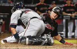  ?? PHOTOS BY JENNIFER STEWART / GETTY IMAGES ?? The Diamondbac­ks’ Nick Ahmed is tagged out at home by Braves catcher Kurt Suzuki in the 10th inning at Chase Field on Sept. 8 in Phoenix. The Braves won 5-4.