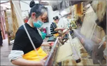  ?? LIU CHAN / XINHUA ?? Two workers weave xiabu cloth on traditiona­l looms at a workshop in Rongchang, Chongqing.