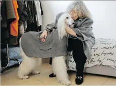  ?? LUCA BRUNO/THE ASSOCIATED PRESS ?? Designer Giovanna Temellini with her Afghan greyhound Ulisse, wearing a winter coat at Temellini manufactur­ing headquarte­rs in Milan. Temellini launched Dog a Porter a year ago.