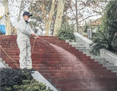  ?? GETTY IMAGES ?? A worker uses alcohol to disinfect the grounds around the Wuhan Huoshensha­n hospital constructi­on site Tuesday in Wuhan, China. The 1,000-bed hospital is expected to be ready for use next week as part of an effort to contain the coronaviru­s outbreak.