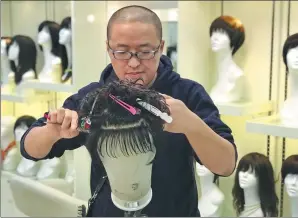  ?? HE QI / CHINA DAILY ?? Qin Kang works on a wig in his salon, Pinqin Wig, in Shanghai.