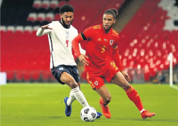  ??  ?? Wales’ Tyler Roberts battles for possession with England’s Joe Gomez. Below left, Wales goalkeeper Wayne Hennessey is helpless as Dominic Calvert-lewin heads home the opening goal of the game on his England debut. Below right, Wales manager Ryan Giggs, right, and England’s Gareth Southgate share a conversati­on before the game at Wembley last night