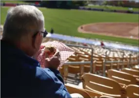  ?? JOHN LOCHER - THE ASSOCIATED PRESS FILE PHOTO ?? In this March 4, 2015 file photo, a fan eats a hot dog before a spring training exhibition baseball game between the Chicago White Sox and the Los Angeles Dodgers, in Phoenix. Owners who take customers to sporting events or the theater or treat them to a round of golf will have to foot the entire bill for those activities. The new tax law has done away with the entertainm­ent deduction for businesses.