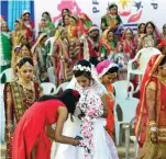  ??  ?? A Christian bride to be, Daxa, is helped by her friend at a mass wedding of 236 fatherless girls organized by the PP Savani Group.