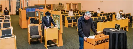  ??  ?? Dr. Daniel Goodman (center right) leads a weekday service at Congregati­on Beth Tefillah in Sandy Springs on March 11 while Rabbi Yossi New works on the Zoom connection.
Because it is an Orthodox synagogue, the use of technology is limited and not used at all on the Sabbath, New said.