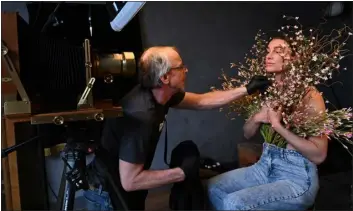  ?? ?? Tintype photograph­er Tim Brown styles flowers around Corey Hubbard’s face as she poses while getting her photograph taken in his studio on March 20in Salida, Colorado. Brown says that the experience of getting a tintype photograph is fun and unique. “It’s rare that people don’t leave with a new appreciati­on of the process,” he says. Clients can choose from a collection of hats or clothes and other objects in his studio to add interestin­g elements to the photograph.