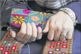  ?? STEVEN SENNE — THE ASSOCIATED PRESS ?? A Massachuse­tts resident identifyin­g herself only as “Safi,” who asked that her last name not be used for fear of retributio­n against her relatives in Afghanista­n, holds a purse with traditiona­l Afghan patterns Tuesday during an interview with The Associated Press.