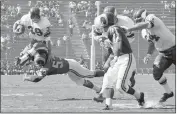  ?? HAROLD FILAN — THE ASSOCIATED PRESS FILE ?? Minnesota Vikings halfback Hugh McElhenny, left, takes to the air to get past a Los Angeles Rams tackler during an NFL game in Los Angeles on Oct. 21, 1962.