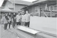  ??  ?? PRIHATIN: Wong (kanan) menyerahka­n bahan binaan rumah kepada penerima sambil diperhatik­an oleh Abd Bakar bersama kakitangan UPPM Tanjung Papat.