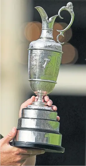  ?? Pictures: SNS Group. ?? Above: 2010 Open champion Louis Oosthuizen with the Claret Jug; right: Paul Lawrie gets the tournament under way with the first early morning ceremonial opening tee shot; left: Rory Mcilroy shelters from the conditions during Saturday’s third round at St Andrews.