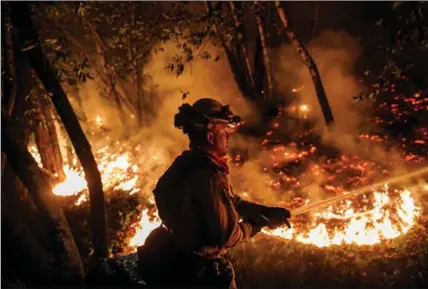  ?? MARCUS YAM, TNS ?? Firefighte­r Mario Topete attacks flames as his unit tries to prevent a fire from crossing Highway 29 near Calistoga earlier this month.