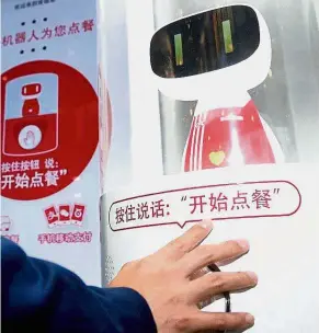  ?? — Xinhua ?? Service of the future: A customer placing an order using a virtual personal assistant robot during the opening day of the KFC concept outlet in Shanghai.