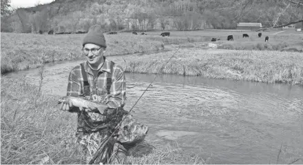  ?? PAUL A. SMITH ?? John Motoviloff holds a brown trout caught on Tainter Creek in Crawford County. This section of the stream, which features gently sloping banks as it passes through a farm with cattle, was undamaged by floods.