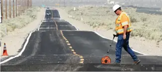  ?? (David McNew/Reuters) ?? A WORKER measures newly ruptured ground after an earthquake east of Ridgecrest, California, on Saturday.