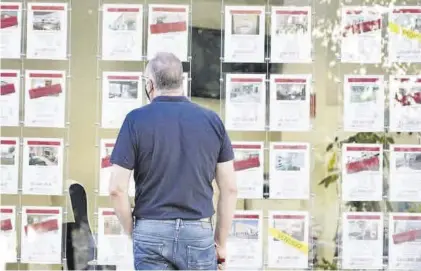  ?? EL PERIÓDICO ?? Un hombre mira anuncios de pisos expuestos en el escaparate de una inmobiliar­ia.