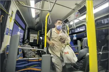  ?? Francine Orr Los Angeles Times ?? MARIO BLANCO gets on a bus in Long Beach with his dog. After saying that emergency housing vouchers would be suspended, L.A. County now says unhoused voucher holders will be matched with another subsidy.