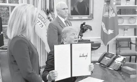  ??  ?? U.S. Homeland Security Secretary Kirstjen Nielsen and Vice-President Mike Pence look on Wednesday at the White House as President Donald Trump holds up his signed executive order halting his administra­tion’s policy of separating children from their...