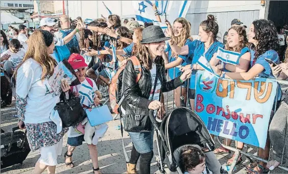  ?? JACK GUEZ / AFP ?? Bienvenida. Inmigrante­s judíos franceses son recibidos al llegar al aeropuerto de Ben Gurion el lunes; abajo, un niño besa el suelo israelí