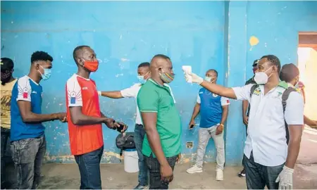  ?? DIEU NALIO CHERY/AP ?? Health ministry workers check the temperatur­e of fans entering a stadium before a soccer match March 25 in Port-au-Prince, Haiti.