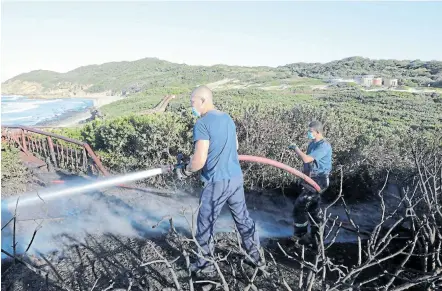  ?? Picture: ALAN EASON ?? DELIBERATE DAMAGE? BCM firefighte­rs extinguish a fire along the Nahoon Boardwalk where a 28m section and a lookout spot was destroyed. A forensic investigat­ion will determine what caused the fire, which is believed to have started at the lookout platform.