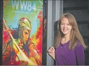  ?? (The Frederick News-Post) ?? Caroline Coleman, 20, stands next to the Wonder Woman 1984 movie poster in Frederick, Md. The Urbana High School class of 2019 graduate played the shoplifter in the feature film.