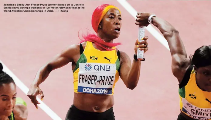  ??  ?? Jamaica's Shelly-Ann Fraser-Pryce (center) hands off to Jonielle Smith (right) during a women's 4x100-meter relay semifinal at the World Athletics Championsh­ips in Doha. — Ti Gong