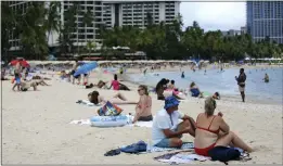  ?? CALEB JONES — THE ASSOCIATED PRESS ?? Brett Walsh and Emma Yates, bottom right, tourists from Australia, sit on Waikiki Beach in Honolulu on Monday to enjoy the Hawaiian sand, surf and sun with others.