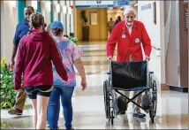  ?? PHOTOS BY PHIL SKINNER ?? Volunteer J.C. Palmer pushes a wheelchair through WellStar Kennestone Hospital in Marietta. He and other volunteers pushing wheelchair­s can walk up to 4 miles in one shift.