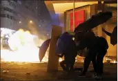  ?? VINCENT YU — THE ASSOCIATED PRESS ?? Protesters cover with umbrellas from tear gas canister in the Kowloon area of Hong Kong on Monday.