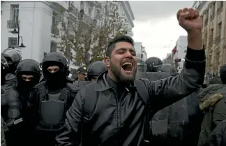  ?? AP ?? A protester faces off with riot police during a demonstrat­ion in Tunis yesterday. Days of clashes with police have left one person dead, dozens injured and hundreds arrested.