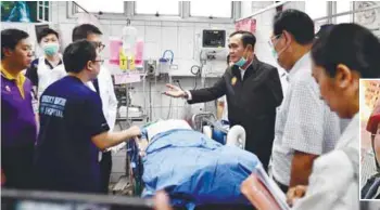  ??  ?? Prayut (third from right) visits a patient at the Maharat Nakhon Ratchasima Hospital in the Thai northeaste­rn city of Nakhon Ratchasima yesterday. – AFPPIX