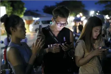  ??  ?? People check their mobile phones for update while waiting at a military airbase during emergency helicopter evacuation in Chiang Rai province, northern Thailand, Monday, July 9, 2018. Four more of the boys trapped for over two weeks in a flooded cave in northern Thailand were brought out on Monday, an official said, bringing to eight the number extracted in a high-stakes rescue operation.