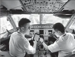  ?? TANG KE / FOR CHINA DAILY ?? An aircraft commander of China Eastern Air Holding Co discusses the flight plan with his co-pilot in the plane.