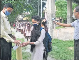  ?? ANI ?? Students sanitize their hands before entering school as it reopened following a gap of more than seven months due to coronaviru­s pandemic, in Guwahati on Monday.