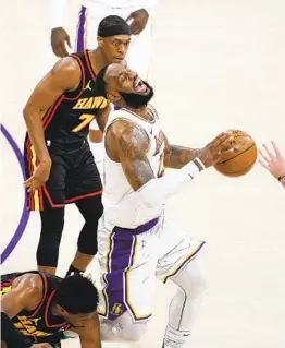  ?? MARCIO JOSE SANCHEZ AP ?? Lakers forward Lebron James grimaces as he trips and injures himself over Hawks forward Tony Snell (bottom) during the first half Saturday.