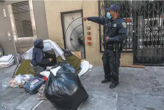  ??  ?? Officer B. Holbrook speaks to a woman staying in a small tent encampment on the corner of Taylor and Ellis, asking her about moving into a hotel like many former street campers.