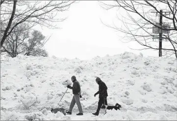  ?? ABEL URIBE/CHICAGO TRIBUNE ?? A couple of men and their dogs walk by a mountain of snow across from the VA hospital in the west side Feb. 6.