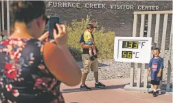  ?? MELINA MARA/WASHINGTON POST ?? With record high temperatur­e reaching 135 degrees Saturday, tourists stop at a visitors center in Death Valley, Calif., to pose with the thermomete­r.