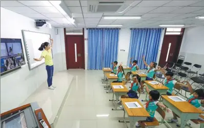  ?? XINHUA ?? With the help of online distance education system, teacher Zhang Li (left) guides a music class at Yongxing School in Sansha, Hainan province, together with another class in Binhai No 9 Elementary School in Haikou, the provincial capital of Hainan.