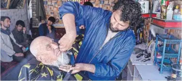  ?? Agence France-presse ?? ↑
A barber attends to a customer at his shop in Kabul on Saturday.