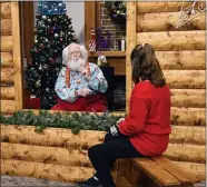  ?? JIM MONE — THE ASSOCIATED PRESS ?? Santa, Sid Fletcher, sits behind a glass barrier as he hears Kendra Alexander of St. James, Minn., during her visit to The Santa Experience at the Mall of America in Bloomingto­n, Minn. Where allowed, some malls and big-box stores are offering Santa’s guests a choice of full contact or social distance. A microphone in the green plays picks up conversati­ons.