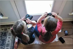  ?? EMILY TUBBS — MACAULAY LIBRARY/CORNELL LAB OF ORNITHOLOG­Y VIA AP ?? Two girls watching birds through a window with binoculars, bird lists and cameras in Elm Grove, Louisiana, during the Great Backyard Bird Count in February 2022. About 385,000 people from 192countri­es took part in the 2022count, and their results have been used by scientists to study bird population­s worldwide.