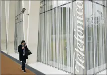  ?? File picture: REUTERS ?? OBSTRUCTED: A woman walks past a Telefonica building in Barcelona, Spain. Telefonica was planning to sell O2 to pay down some of its debt.