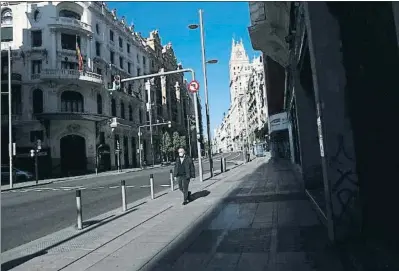  ?? SUSANA VERA / REUTERS ?? Un hombre se protege con una mascarilla mientras camina por una solitaria Gran Vía madrileña