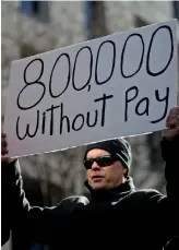  ?? Reuters ?? A demonstrat­or holds a sign, signifying hundreds of thousands of federal employees who won’t be receiving their paychecks as a result of the partial government shutdown, in Washington. —