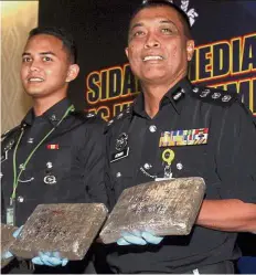  ??  ?? Confiscate­d: ACP Adnan (right) and Investigat­ion Officer Inspector Alifah Alif showing some of the seized packs of compressed cannabis at the press conference.