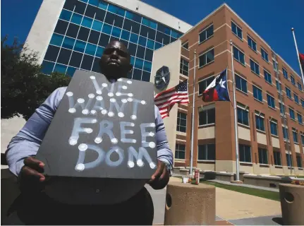  ?? (Carlo Allegri/Reuters) ?? A MAN holds a sign at police headquarte­rs earlier this week following the multiple police shootings in Dallas, Texas.