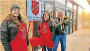  ?? [PHOTO BY CARLA HINTON, THE OKLAHOMAN] ?? Rikki Ross and Elsa Robles, volunteers from Farmer’s Insurance, man The Salvation Army red kettle Monday at an entrance to the J.C. Penney store as Robles’ husband, Andy, plays Christmas carols on his trombone at Quail Springs Mall in Oklahoma City.