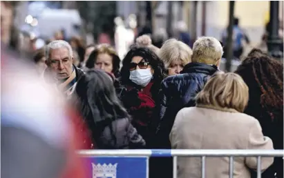  ?? Foto: dpa ?? Eine Frau mit Mundschutz wartet vor der Kirche des Cristo de Medinaceli in Madrid.