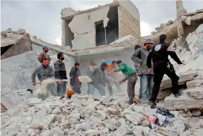  ??  ?? Rescuers and civilians inspect a destroyed building in the Syrian village of Kfar Jales, on the outskirts of Idlib, following air strikes by Syrian and Russian warplanes on Wednesday.